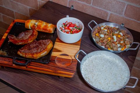 Bifes grelhados na chapa com pão de alho, molho e feijão tropeiro do Tempero da Bisa